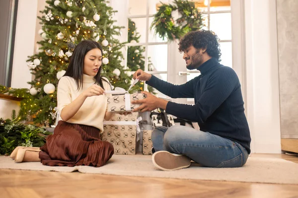 Man and woman opening gift box sitting on floor — стоковое фото