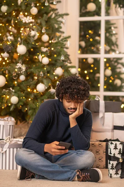 Man kijkt naar smartphone zitten op de vloer — Stockfoto