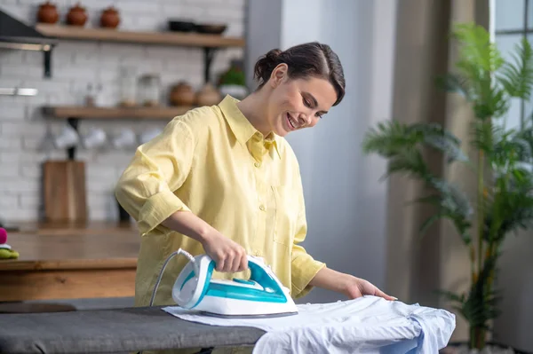 Usmívající se krásná žena v domácnosti žehlení vrásčité košile — Stock fotografie