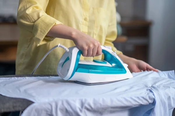 Female hands ironing wrinkled clothes on the ironing-board — Stockfoto