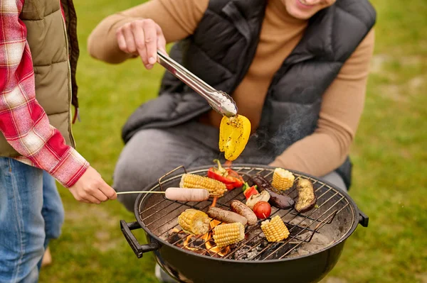 Man crouched near barbecue with vegetables — Stock Photo, Image