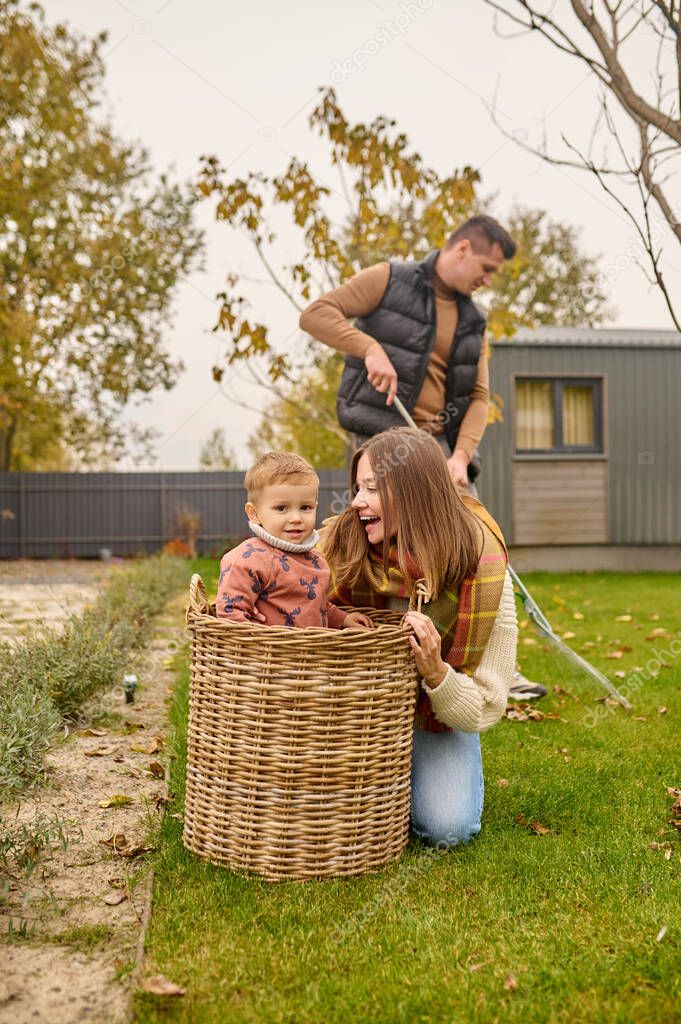 Joyful woman crouching looking at child in basket outdoors