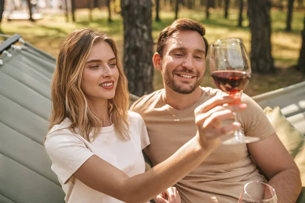 Pasangan muda tersenyum memegang gelas dengan anggur dan tampak bahagia — Stok Foto