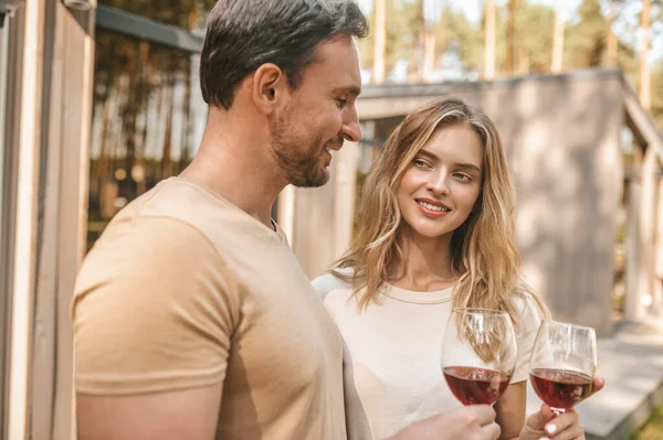 Young smiling couple holding glasses with wine and looking happy — ストック写真