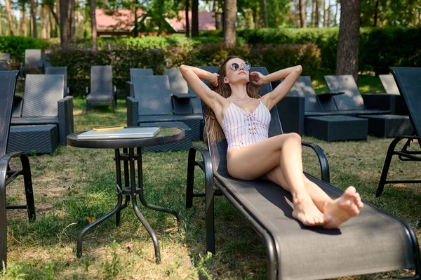 Uma mulher bonita em óculos de sol tomar banho de sol e olhar relaxado — Fotografia de Stock