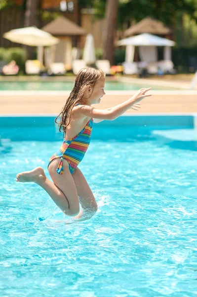 A girl jumping into the water at the swimming pool — Fotografia de Stock