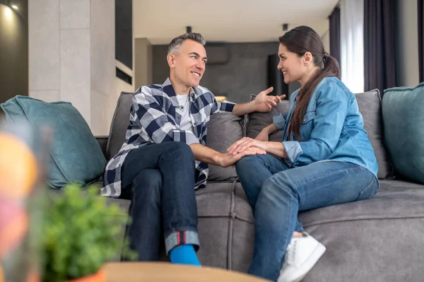 Woman looking at rejoicing man sitting on sofa — Stock Photo, Image