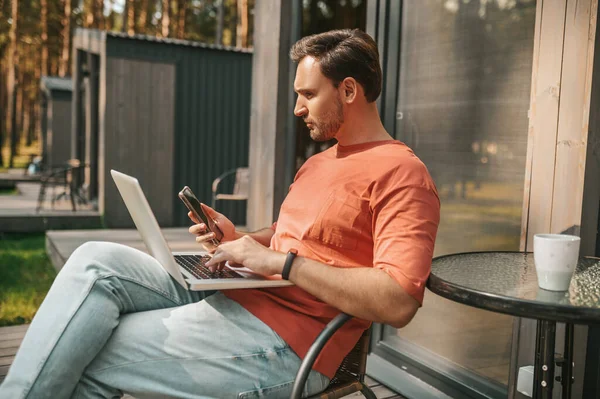 Een jongeman met een laptop die buiten zit en online werkt — Stockfoto