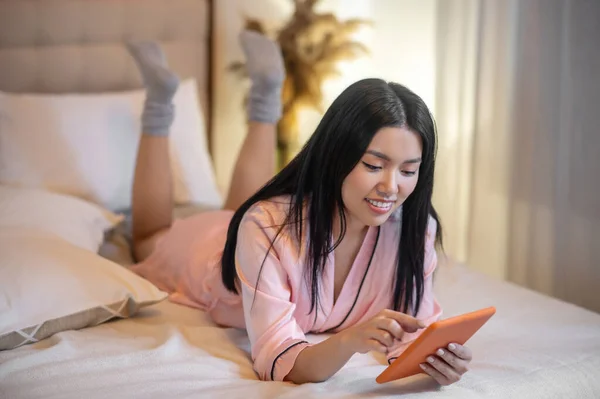 Wanita melihat tablet berbaring di tempat tidur — Stok Foto