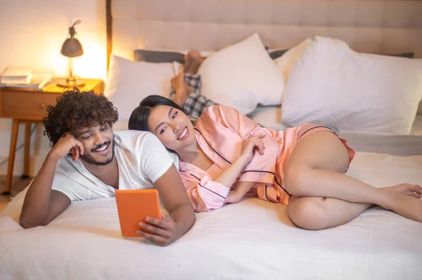 Woman leaning on man lying with tablet — Stockfoto