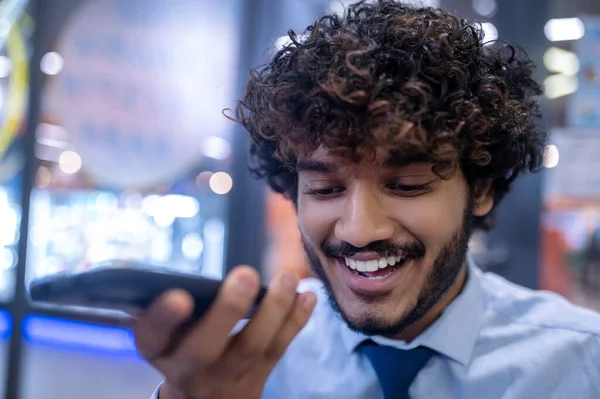 Curly-haired young businessman recording a voice message — стоковое фото