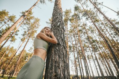 Sarışın kadın parkta vakit geçirirken kendini rahat ve huzurlu hissediyor.