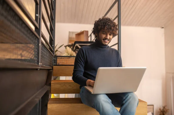 Man looking at laptop screen sitting on stairs — 图库照片