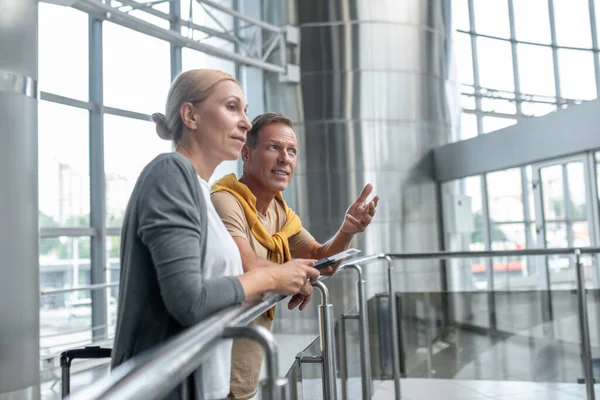 Hombre hablando con su compañera pensativa en el aeropuerto — Foto de Stock