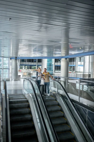 Airport passengers scrutinizing travel documents on the escalator — Stockfoto