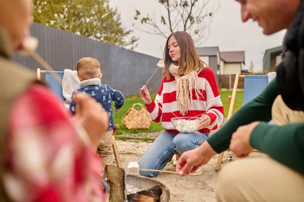 Woman looking with pleasure at marshmallows on stick — Stock Photo, Image