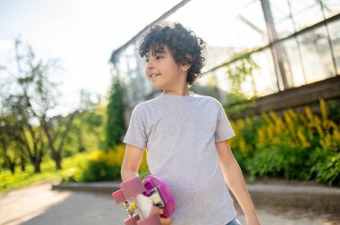 Young skateboarder with the board in his hand looking away