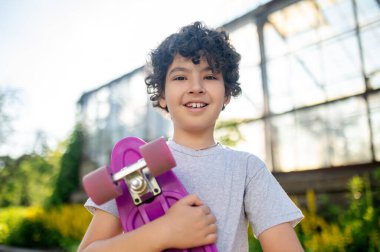 Joyous young skateboarder looking in front of him