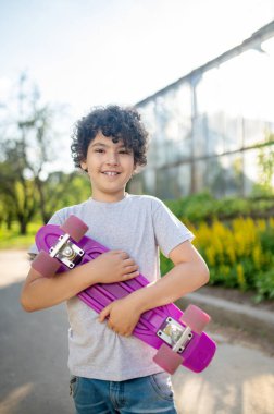 Young boy skateboarder posing for the camera outdoors