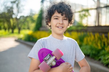 Boy skateboarder standing outdoors and looking ahead