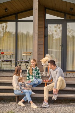 Parents looking at their daughter communicating on steps of house