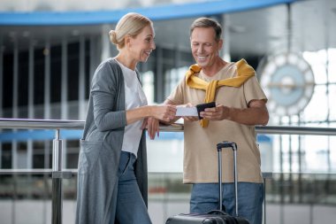 Cheerful middle-aged couple standing at the airport terminal