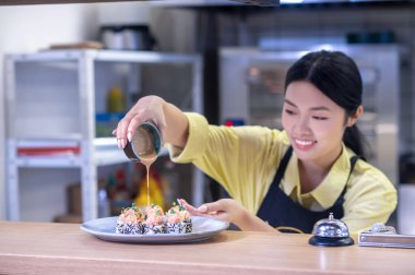 Asian woman putting sushi on the plate and looking inspired