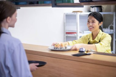 Asian waitress serving sushi to the customer