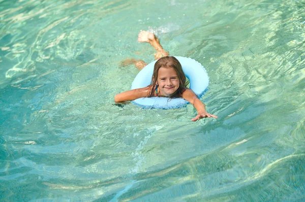 Sweet little girl swimming on a tube and smiling — Stok fotoğraf