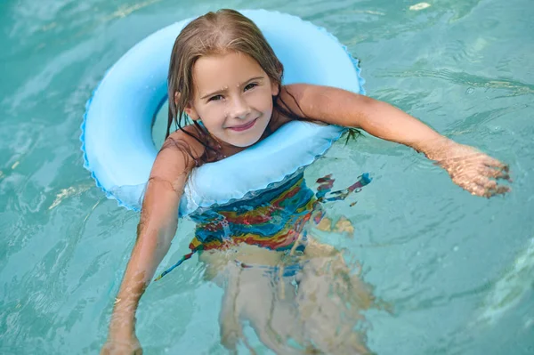 Sweet little girl swimming on a tube and smiling — Stock Fotó