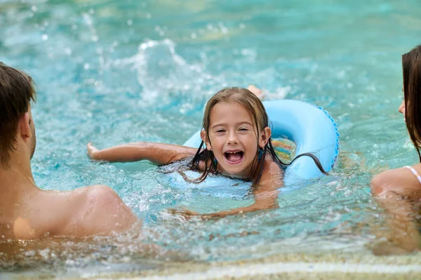 Cute girl and her parents spending time at the swimming pool — Stok fotoğraf