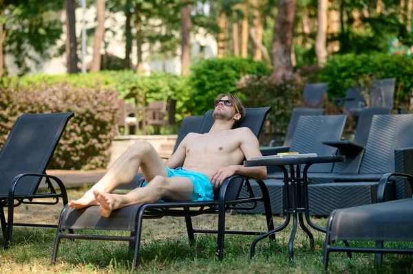 Young man in blue shorts sunbathing and looking relaxed — Stockfoto
