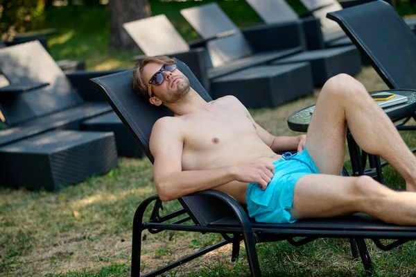 Young man lying in a chaise longue and looking relaxed — Stok fotoğraf