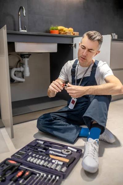 Man looking at detail sitting on floor — Stock Photo, Image