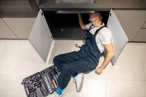 Top view of man lying on floor repairing sink — Stock Photo, Image