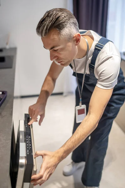 Man standing leaning towards dishwasher looking at control panel — Fotografia de Stock