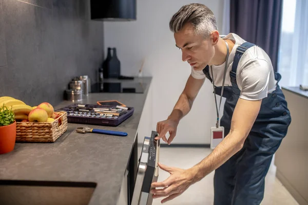 Man looking at information on control panel of dishwasher — Stockfoto