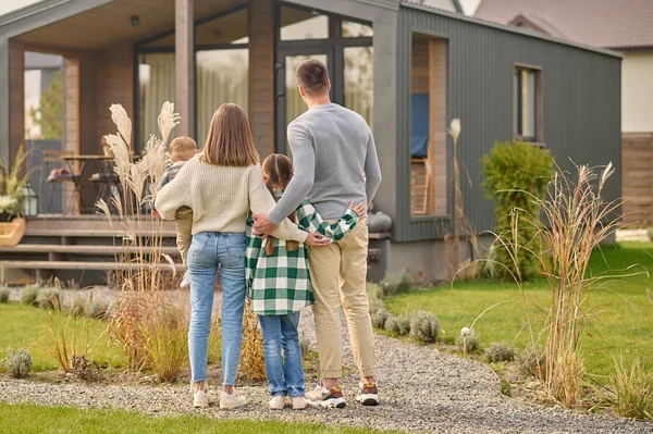 Back view of family hugging and admiring their home — Foto de Stock