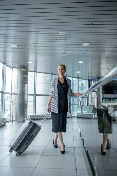 Señora de negocios agradable con el equipaje de pie en el aeropuerto — Foto de Stock