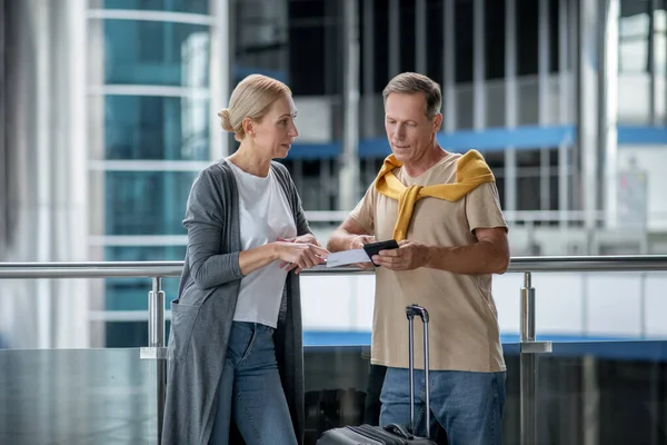 Airport passenger talking to a male with travel documents — Stockfoto