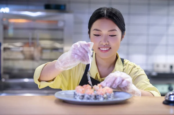 Mujer asiática poniendo sushi en el plato y buscando inspirado — Foto de Stock