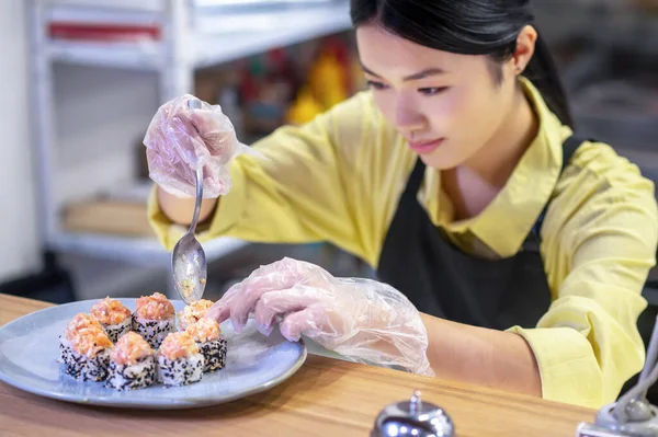 Mujer asiática poniendo sushi en el plato y buscando inspirado — Foto de Stock