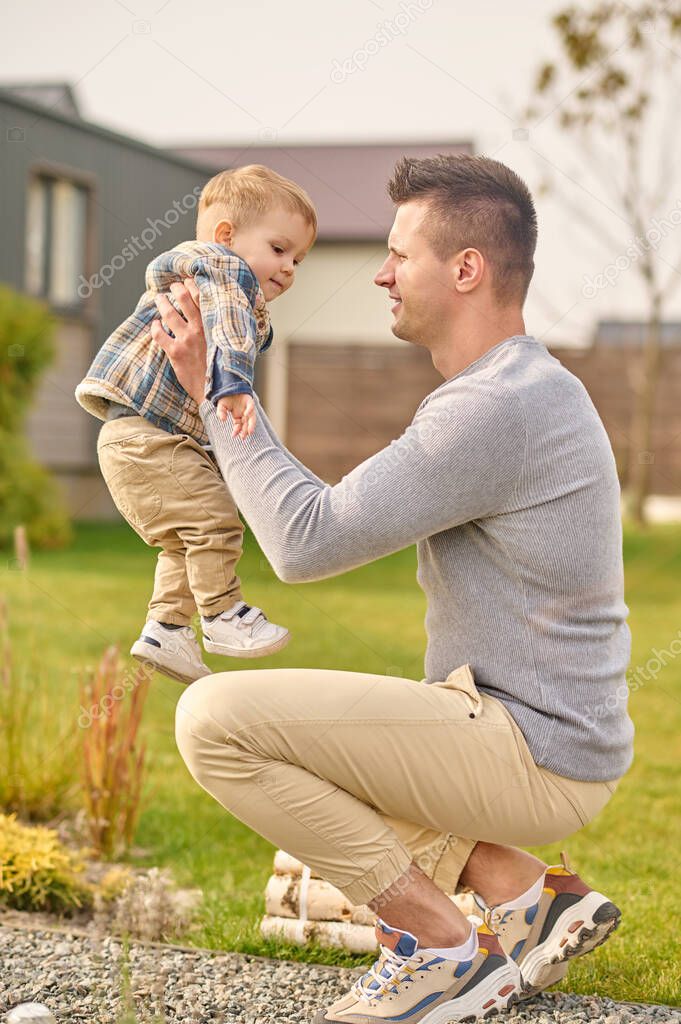 Man sitting sideways to camera and raising child