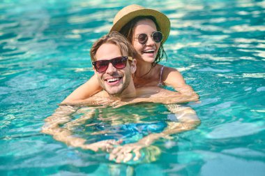 Young happy couple spending time in a swimming pool