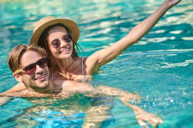 Young happy couple spending time in a swimming pool