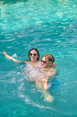 Young couple swimming in a pool and feeling excited
