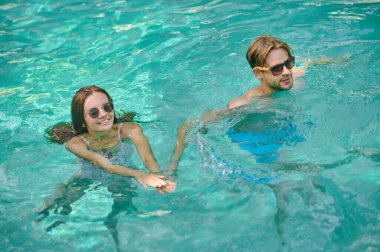 Young couple swimming in a pool and feeling excited