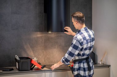 Back view of man touching kitchen appliance hanging on wall