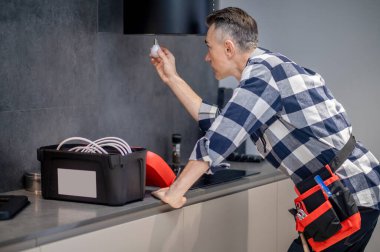 Man with lamp in hand looking at kitchen hood