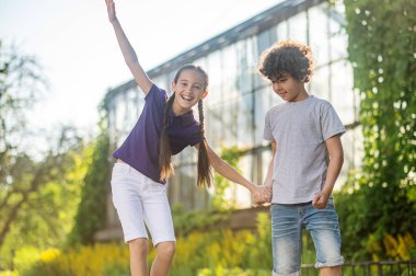 Joyous dark-haired girl learning to skateboard outdoors